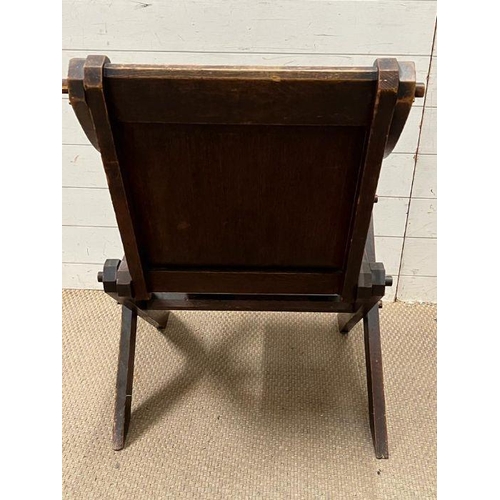 258 - A solid oak Tudor Revival Glastonbury chair, with shaped arms and x frame legs with joints held with... 