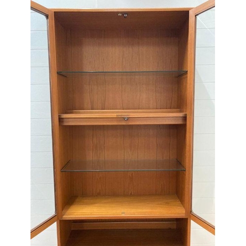 66 - A G-Plan wall unit with two glazed doors and three shelves to top and a two door cupboard to bottom ... 