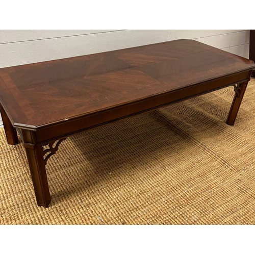 172 - A long low coffee table with carved corner supports (132cm x 58cm)