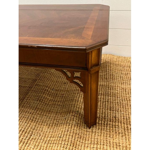 172 - A long low coffee table with carved corner supports (132cm x 58cm)