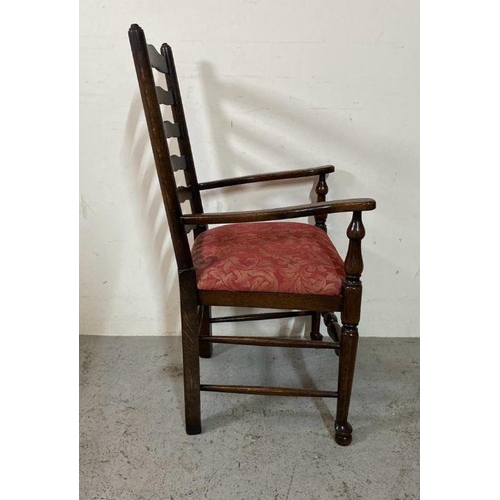 208 - An oak spool turned ladder back arm chair upholstered in red