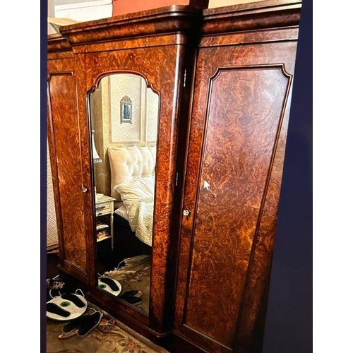 216 - A Victorian burr walnut triple wardrobe. A breakfront shape top cornice above three doors, two with ... 