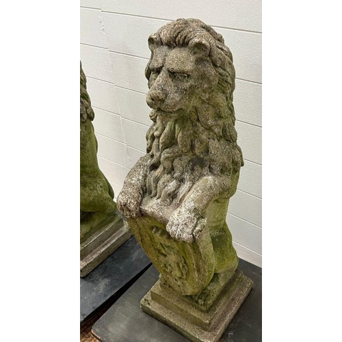 285 - A pair of reclaimed garden lion statues holding shields on pier caps