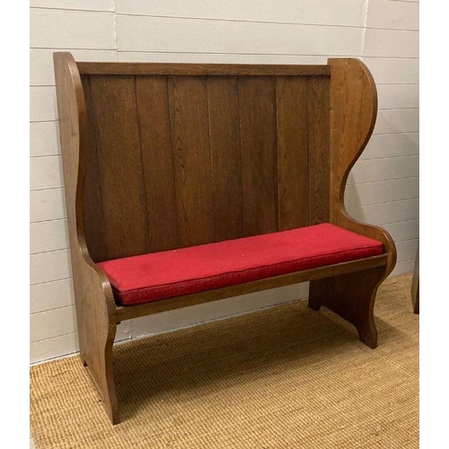 33 - An oak vintage two seater settle with red upholstered cushions (H123cm W122cm Seat Depth 39cm)