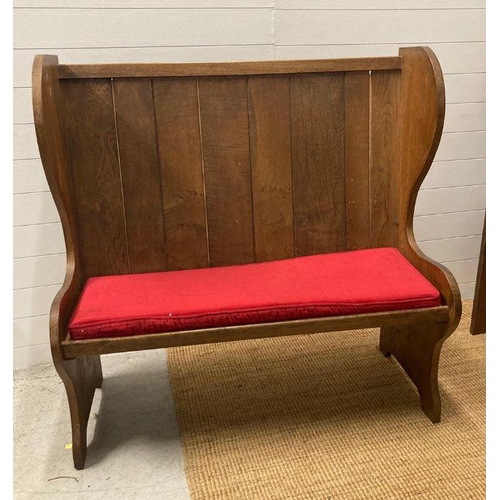 34 - An oak vintage two seater settle with red upholstered cushions (H123cm W122cm Seat Depth 39cm)