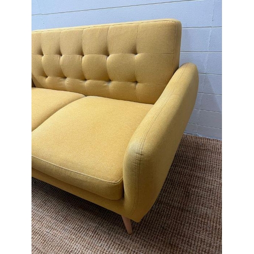 41 - A Mid Century style mustard upholstered two seater button back sofa