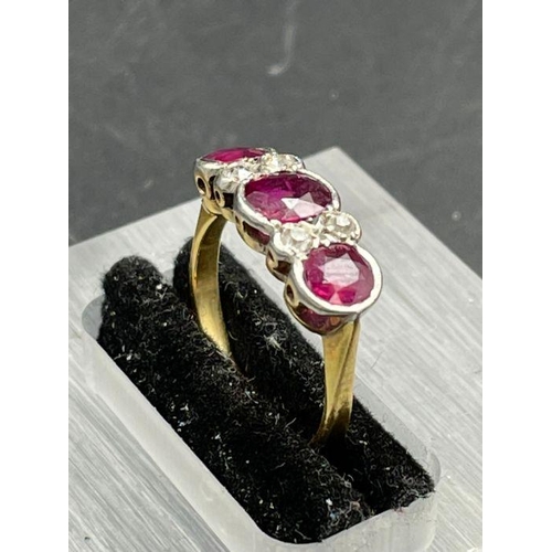 479 - An Antique three stone ruby ring with four small diamonds. Size K