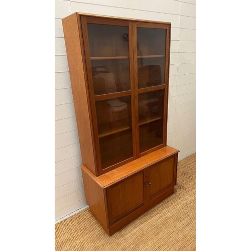 51 - A glazed teak bookcase with cupboard under by Turnbridge of London (H176cm W90cm D43cm)