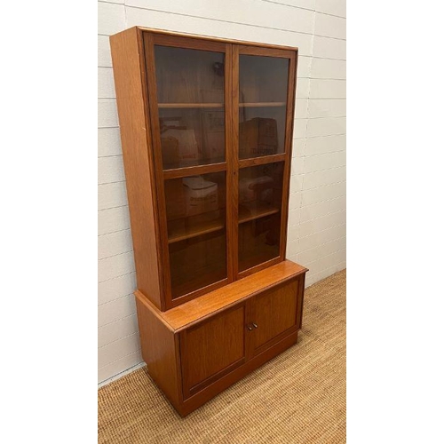 51 - A glazed teak bookcase with cupboard under by Turnbridge of London (H176cm W90cm D43cm)