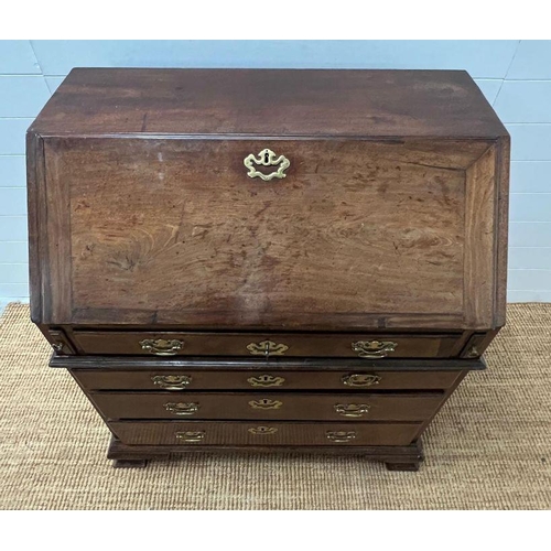 70 - A George III bureau, the fall front enclosing drawers and recesses around a central door along with ... 