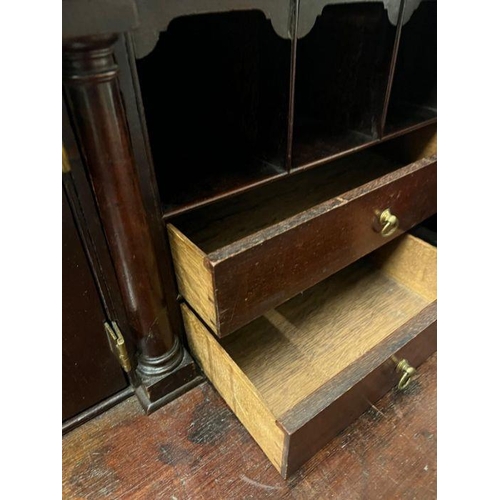 70 - A George III bureau, the fall front enclosing drawers and recesses around a central door along with ... 