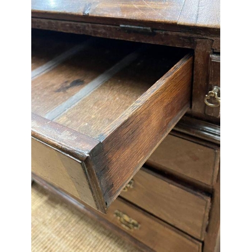 70 - A George III bureau, the fall front enclosing drawers and recesses around a central door along with ... 