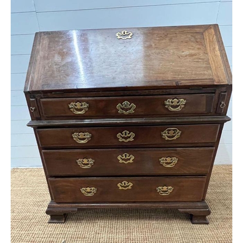 70 - A George III bureau, the fall front enclosing drawers and recesses around a central door along with ... 