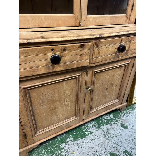 28 - An antique pine glazed dresser, the glazed top hinged doors opening to shelves and a cupboard base w... 