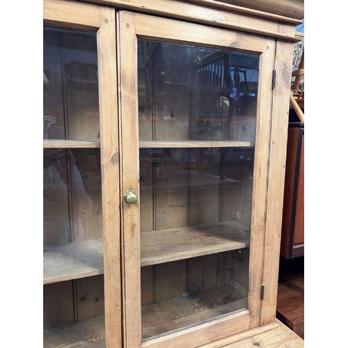 28 - An antique pine glazed dresser, the glazed top hinged doors opening to shelves and a cupboard base w... 