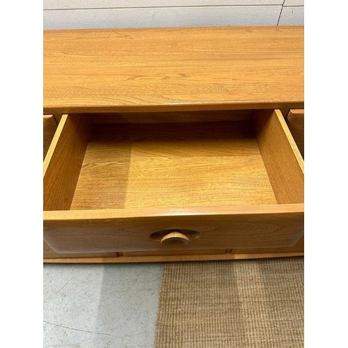 30 - An Ercol sideboard with three drawers and three cupboards under