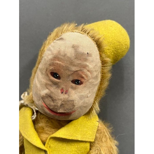 42 - A vintage monkey with jointed arms and legs, leather hands and feet wearing a yellow felt hat and wa... 