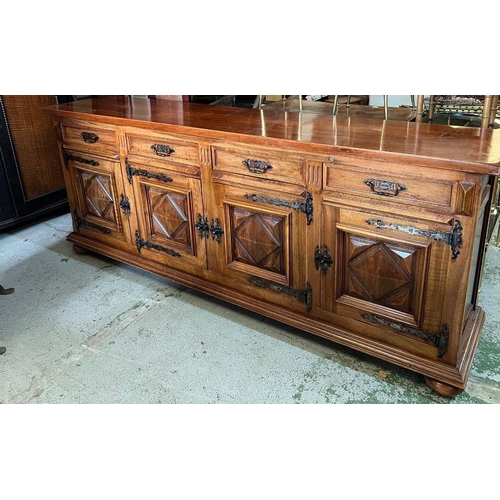 46 - A long hardwood sideboard on bun feet consisting of four drawers and four cupboards with wrought iro... 