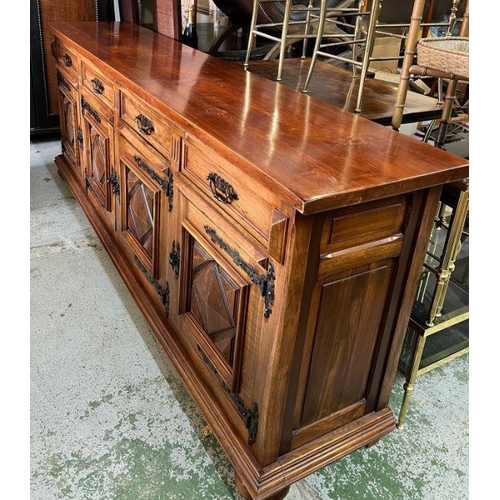 46 - A long hardwood sideboard on bun feet consisting of four drawers and four cupboards with wrought iro... 
