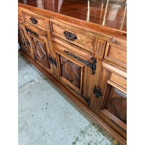 46 - A long hardwood sideboard on bun feet consisting of four drawers and four cupboards with wrought iro... 