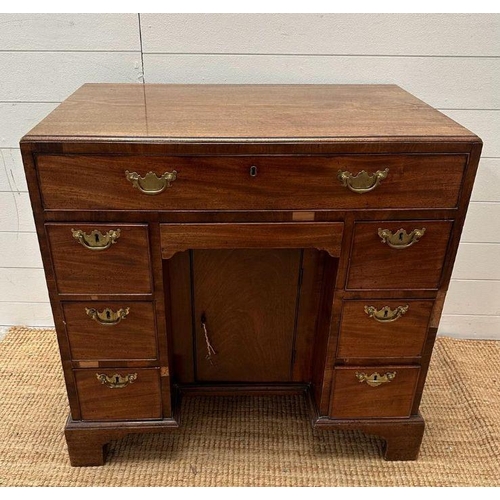 8 - An oak kneehole desk with centre cupboard flanked by three drawers to left and right with brass drop... 