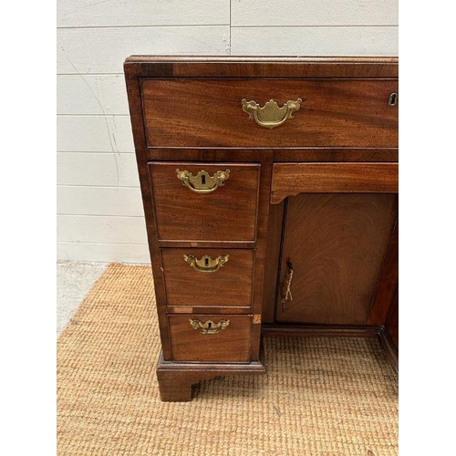 8 - An oak kneehole desk with centre cupboard flanked by three drawers to left and right with brass drop... 