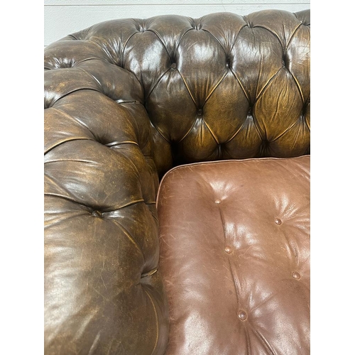 125 - A brown leather Chesterfield style button back three seater sofa on bun feet (H72cm D91cm W186cm)