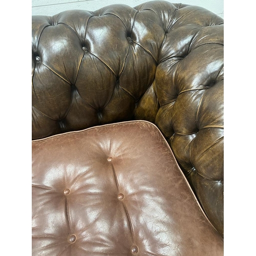 125 - A brown leather Chesterfield style button back three seater sofa on bun feet (H72cm D91cm W186cm)