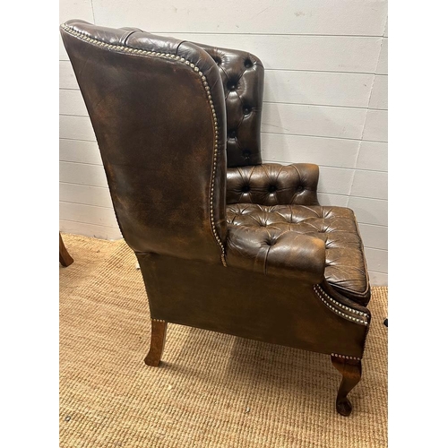 130 - A pair of brown leather Chesterfield style wing back arm chairs (H107cm D68cm)