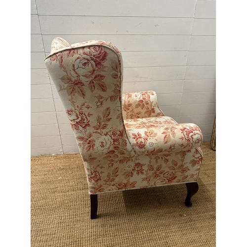 145 - A white ground floral upholstered wing back arm chair on cabriole legs (H110cm W78cm D70cm)