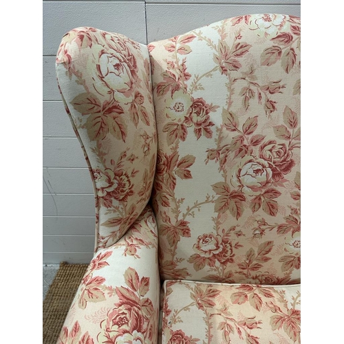 145 - A white ground floral upholstered wing back arm chair on cabriole legs (H110cm W78cm D70cm)