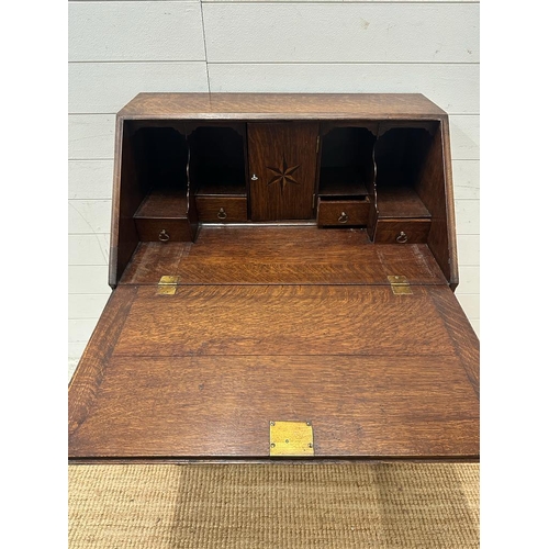 148 - An oak bureau on barley twist support and cross stretcher with single drawer and brass drop handles ... 