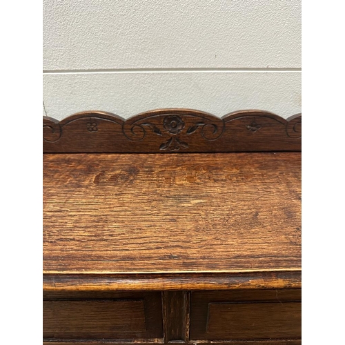 149 - A four shelf oak bookcase with two drawers over and carved floral gallery (H117cm W93cm D23cm)