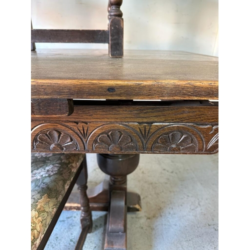 156 - An oak Arts and Crafts style extending dining table on carved supports and cross stretcher  with two... 