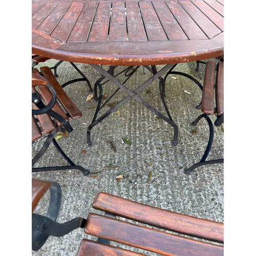 168 - A Teak Garden circular table with wrought iron folding legs along with six matching chairs.