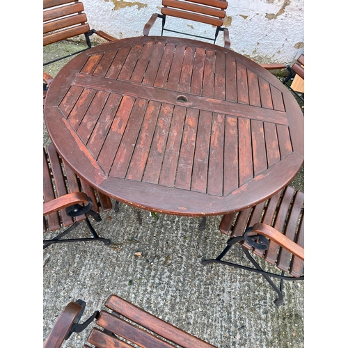 168 - A Teak Garden circular table with wrought iron folding legs along with six matching chairs.