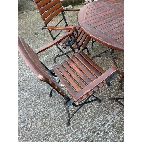 168 - A Teak Garden circular table with wrought iron folding legs along with six matching chairs.