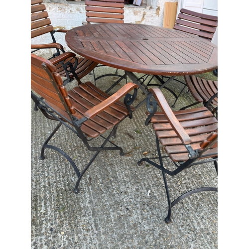 168 - A Teak Garden circular table with wrought iron folding legs along with six matching chairs.