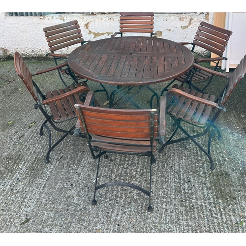 168 - A Teak Garden circular table with wrought iron folding legs along with six matching chairs.