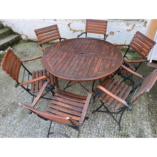 168 - A Teak Garden circular table with wrought iron folding legs along with six matching chairs.