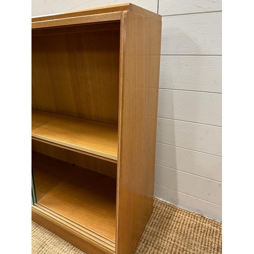 184 - A light oak Mid Century two shelf bookcase with glazed sliding doors (H85cm W91cm D30cm)