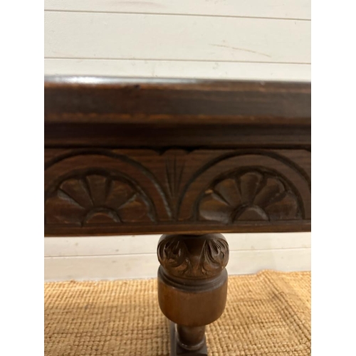 192 - A Mid Century oak coffee table on carved supports with cross stretches (H55cm W133cm D57cm)