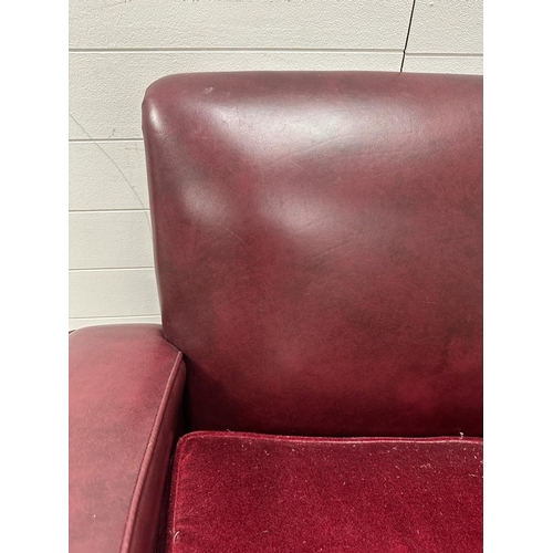 208 - A two seater faux leather oxblood sofa with carved oak arm supports and two matching chairs