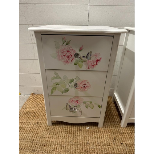 215 - A pair white painted three drawer bedside tables with rose motif (H60cm W42cm D32cm)