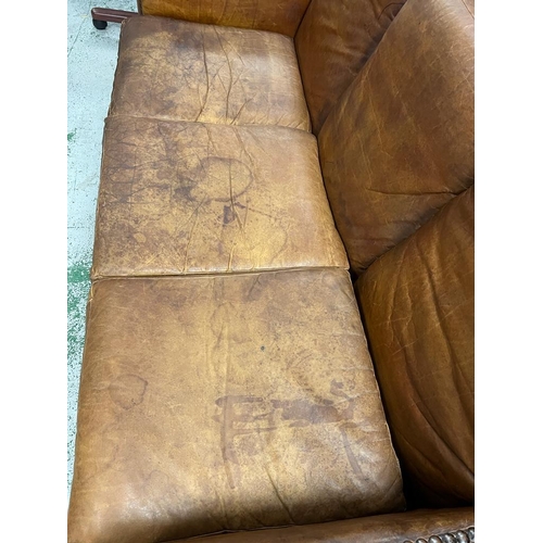 232 - A three seater leather sofa with stud detail to base