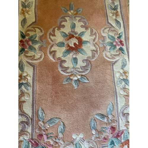 268 - A pink ground rug with central floral motif (126cm x 58cm)