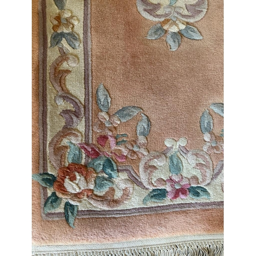 268 - A pink ground rug with central floral motif (126cm x 58cm)