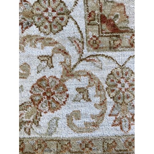 273 - A beige ground rug with floral pattern and geometric boarder (120cm x 190cm)