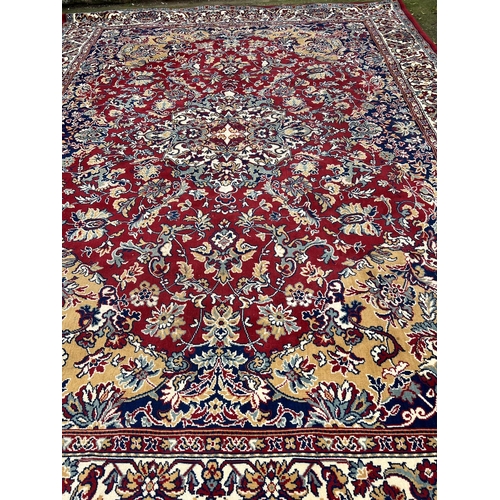 275 - A large red ground rug with geometric pattern 296cm x 396cm