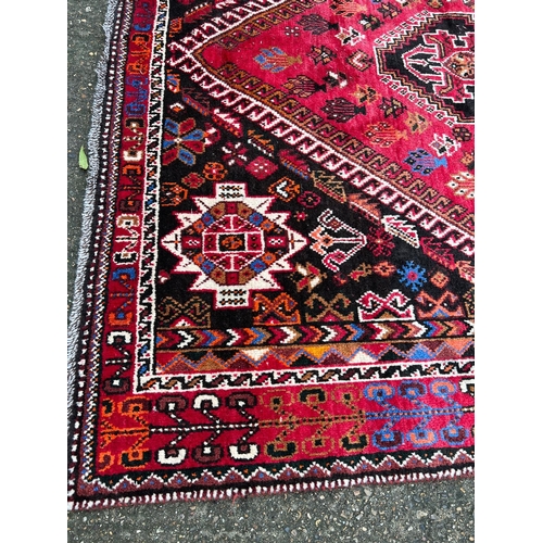 276 - A hand knotted red ground carpet/rug with geometric pattern 204cm x 295cm